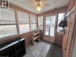 Enclosed sunroom featuring natural wood paneling, multiple windows, a ceiling fan with integrated lighting, a full-light door, and slate tile flooring - 