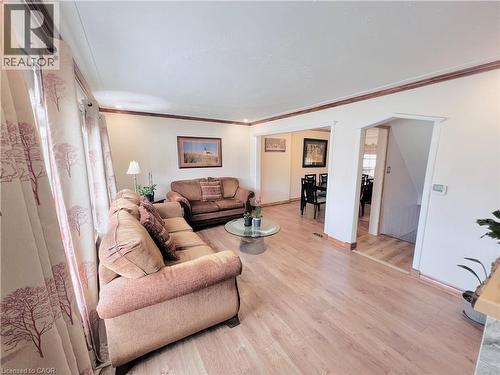 Light wood-finish flooring provides a bright base for this living area with crown molding - 56 Eastvale Place, Hamilton, ON - Indoor Photo Showing Living Room