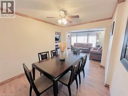 Dining area featuring wood-finish flooring, crown molding, and a ceiling fan with integrated lighting - 