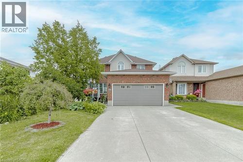 Traditional-style house featuring concrete driveway, a front yard, brick siding, and an attached garage - 32 Vineberg Drive, Hamilton, ON - Outdoor With Facade