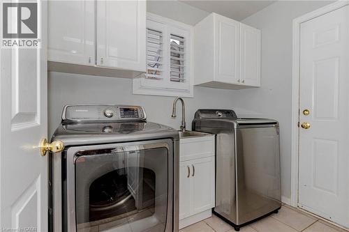 Laundry area featuring washer and clothes dryer, cabinet space, and light tile patterned flooring - 32 Vineberg Drive, Hamilton, ON - Indoor Photo Showing Laundry Room
