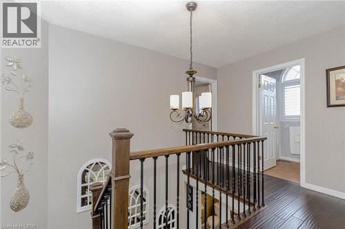Hall with an upstairs landing, a textured ceiling, hanging lights, and wood finished floors - 32 Vineberg Drive, Hamilton, ON - Indoor Photo Showing Other Room
