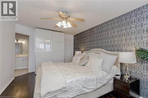 Bedroom with wallpapered walls, an accent wall, dark wood-type flooring, and a ceiling fan - 32 Vineberg Drive, Hamilton, ON - Indoor Photo Showing Bedroom