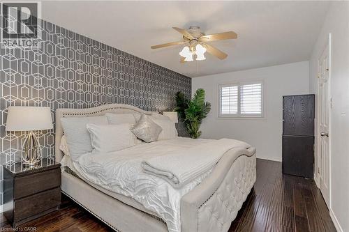 Bedroom featuring an accent wall, wallpapered walls, dark wood-type flooring, and a ceiling fan - 32 Vineberg Drive, Hamilton, ON - Indoor Photo Showing Bedroom