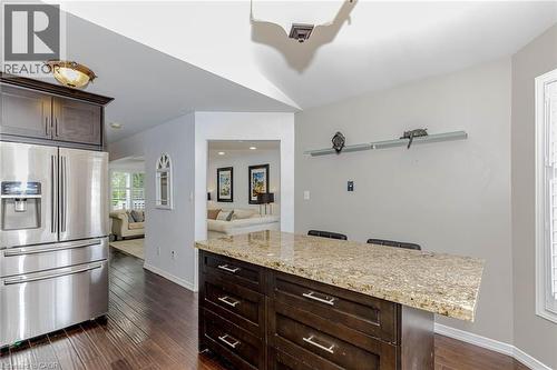 Kitchen featuring dark wood finish cabinets, stainless steel fridge with ice dispenser, a kitchen bar, dark wood-style floors, and light stone countertops - 32 Vineberg Drive, Hamilton, ON - Indoor Photo Showing Other Room