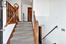 Carpeted staircase with wood-finish balusters and handrails - 