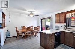 Dining area featuring wood-finish flooring, a ceiling fan with integrated lighting, and white walls - 
