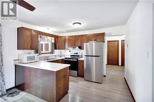 Kitchen featuring wood-finish cabinetry, light-toned countertops, and stainless steel appliances including a refrigerator and range - 16 Sandlewood Avenue, Brantford, ON - Indoor Photo Showing Kitchen