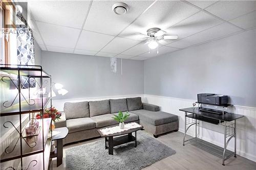 Finished room featuring light-toned walls with wainscoting, wood-finish flooring, a drop ceiling, and a ceiling fan with integrated lighting - 16 Sandlewood Avenue, Brantford, ON - Indoor