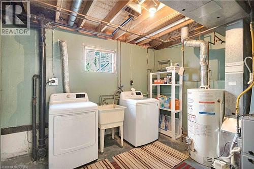 Utility room featuring a laundry sink, exposed beam ceiling, and a window for natural light - 16 Sandlewood Avenue, Brantford, ON - Indoor Photo Showing Laundry Room