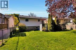 Expansive rear lawn featuring a privacy fence, mature trees, and a storage shed - 