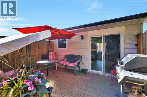 Wood-finish deck with privacy fencing, sliding glass patio door, exterior wall lighting, and a single window - 16 Sandlewood Avenue, Brantford, ON - Outdoor With Deck Patio Veranda With Exterior