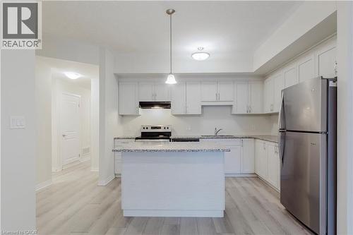 Kitchen with stainless steel appliances, under cabinet range hood, light wood-type flooring, and a sink - 25 Isherwood Avenue Unit# G-105, Cambridge, ON - Indoor Photo Showing Kitchen With Stainless Steel Kitchen With Upgraded Kitchen