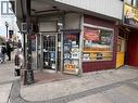 Corner commercial storefront featuring prominent window displays, a red tiled facade, and a glass entrance door - 1 King Street E, Hamilton, ON 