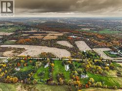 Aerial landscape featuring expansive fields, dense tree lines with autumnal foliage, and scattered residential properties - 