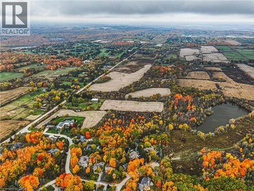 Expansive aerial landscape featuring a residential area surrounded by vibrant autumn foliage, agricultural fields, and a natural pond - 3415 Cedar Springs Road, Burlington, ON 