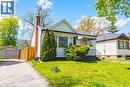 Front exterior featuring white siding, a brick chimney, a striped entrance awning, an asphalt driveway, and an detached garage - 242 East 43Rd Street, Hamilton, ON 
