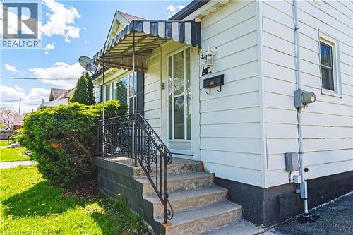 Front entrance featuring a striped awning, concrete steps, and ornamental iron railings - 242 East 43Rd Street, Hamilton, ON - Outdoor With Exterior