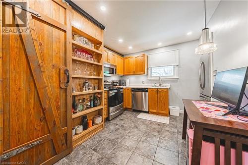 Kitchen featuring a prominent sliding barn door, integrated open shelving, stainless steel appliances, wood-finish cabinetry, and recessed lighting - 242 East 43Rd Street, Hamilton, ON - Indoor Photo Showing Kitchen