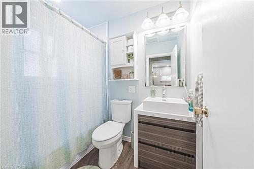Full bathroom featuring a rectangular vessel sink with a single-handle faucet, a wood-grain vanity with two drawers, a mirrored medicine cabinet, and a wall-mounted storage cabinet with open shelving - 242 East 43Rd Street, Hamilton, ON - Indoor Photo Showing Bathroom
