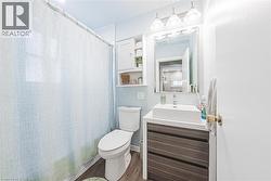 Full bathroom featuring a rectangular vessel sink with a single-handle faucet, a wood-grain vanity with two drawers, a mirrored medicine cabinet, and a wall-mounted storage cabinet with open shelving - 