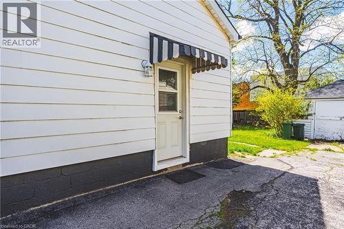 White siding exterior with a black and white striped awning over a cream door - 242 East 43Rd Street, Hamilton, ON - Outdoor