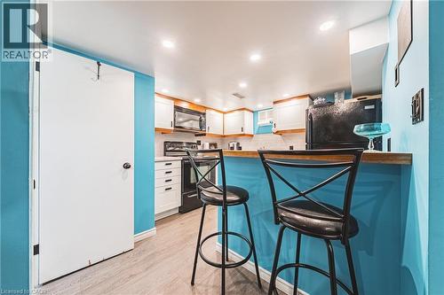 Kitchen featuring a wood-finish breakfast bar, white cabinetry, integrated microwave, and black appliances - 242 East 43Rd Street, Hamilton, ON - Indoor