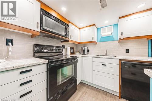 Well-appointed kitchen featuring white cabinetry, light-toned countertops, and a subway tile backsplash - 242 East 43Rd Street, Hamilton, ON - Indoor Photo Showing Kitchen
