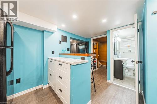 Integrated wet bar featuring a stone-finish countertop and white shaker-style cabinetry - 242 East 43Rd Street, Hamilton, ON - Indoor