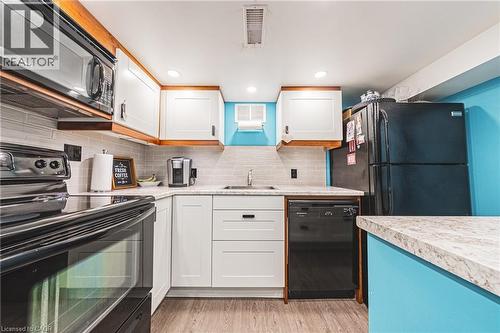 Kitchen featuring white cabinetry with wood-finish trim, light-toned countertops, a light gray subway tile backsplash, and wood-finish flooring - 242 East 43Rd Street, Hamilton, ON - Indoor Photo Showing Kitchen