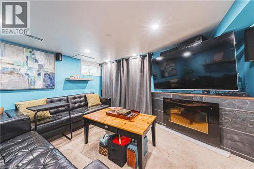 Recreation room featuring recessed lighting, a built-in electric fireplace with a stone-finish surround, a window with horizontal blinds, and a floating shelf - 242 East 43Rd Street, Hamilton, ON - Indoor Photo Showing Other Room With Fireplace