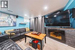 Recreation room featuring recessed lighting, a built-in electric fireplace with a stone-finish surround, a window with horizontal blinds, and a floating shelf - 