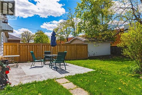 Expansive backyard featuring a concrete patio, wood fencing, a dedicated garage structure, and mature trees - 242 East 43Rd Street, Hamilton, ON - Outdoor