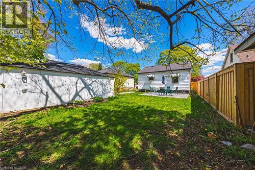 Expansive backyard featuring a concrete patio, a privacy fence, and a detached garage with an exterior light fixture - 242 East 43Rd Street, Hamilton, ON - Outdoor