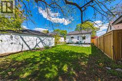 Expansive backyard featuring a concrete patio, a privacy fence, and a detached garage with an exterior light fixture - 