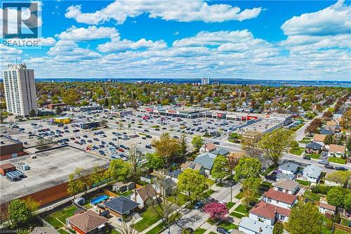 Aerial perspective showcasing a residential neighborhood with a prominent multi-story building, commercial retail center, and a distant body of water - 242 East 43Rd Street, Hamilton, ON - Outdoor With View