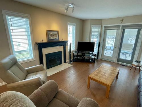 Installed windows on both sides of the living room fire place provides plenty of natural light. - 10 Falcon Place, Brandon, MB 