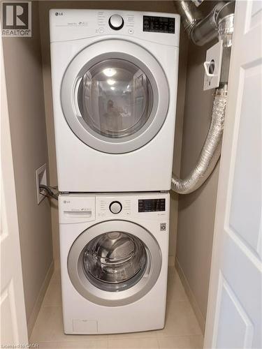 Dedicated laundry alcove featuring a stacked washer and dryer unit, compact design, tile flooring, and neutral wall finishes - 26 Wheat Lane, Kitchener, ON - Indoor Photo Showing Laundry Room