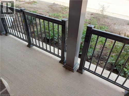 Porch with textured concrete flooring, dark metal railing, and a substantial support pillar - 26 Wheat Lane, Kitchener, ON - Outdoor With Exterior