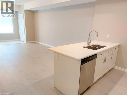 Kitchen island featuring a double basin sink with a gooseneck faucet, light-toned countertop, and integrated stainless steel dishwasher - 26 Wheat Lane, Kitchener, ON - Indoor Photo Showing Kitchen With Double Sink