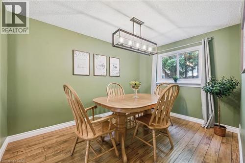 Wood-finish flooring, single window with white trim, green painted walls, and a linear chandelier - 460 Parkview Crescent, Cambridge, ON - Indoor Photo Showing Dining Room