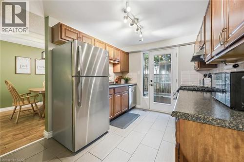 Kitchen featuring wood cabinetry, dark speckled countertops, and light tile flooring - 460 Parkview Crescent, Cambridge, ON - Indoor Photo Showing Kitchen