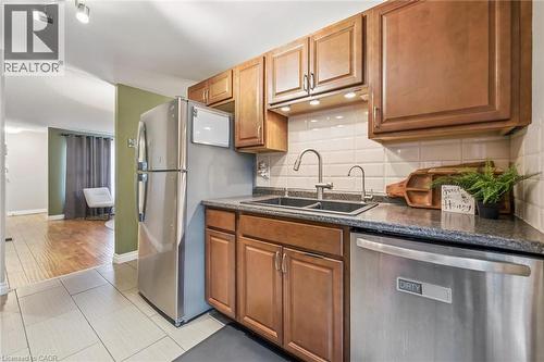Kitchen featuring wood-finish cabinetry, a double basin sink with a gooseneck faucet, a tile backsplash, and recessed under-cabinet lighting - 460 Parkview Crescent, Cambridge, ON - Indoor Photo Showing Kitchen With Double Sink
