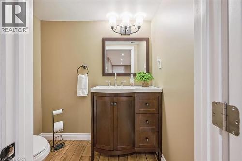 Wood-finish flooring with a rounded vanity featuring a white countertop and rectangular undermount sink - 460 Parkview Crescent, Cambridge, ON - Indoor Photo Showing Bathroom