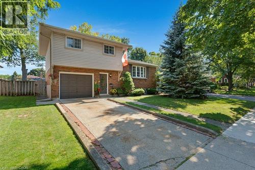 Brick and siding exterior with an attached garage, paved driveway, mature trees, and a manicured lawn - 236 Winston Boulevard, Cambridge, ON - Outdoor