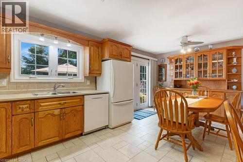 Kitchen with wood cabinetry, light-toned countertops, a tile backsplash, and light-toned tile flooring - 236 Winston Boulevard, Cambridge, ON - Indoor Photo Showing Kitchen With Double Sink