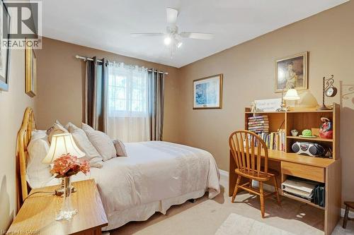 Ceiling fan with integrated lighting, window with curtain rod and drapes, wood-finish headboard, wood-finish nightstand, wood-finish desk with integrated shelving - 236 Winston Boulevard, Cambridge, ON - Indoor Photo Showing Bedroom