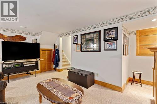 Finished basement recreation room featuring exposed beam ceiling detail, wood-trim framing, neutral carpeting, and built-in entertainment cabinetry - 236 Winston Boulevard, Cambridge, ON - Indoor