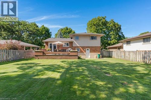 Expansive backyard featuring a manicured lawn, multi-level wood-finish deck, and wood picket fencing - 236 Winston Boulevard, Cambridge, ON - Outdoor With Deck Patio Veranda