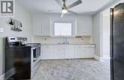 Kitchen featuring white cabinetry, a stainless steel sink, and a window with blinds - 